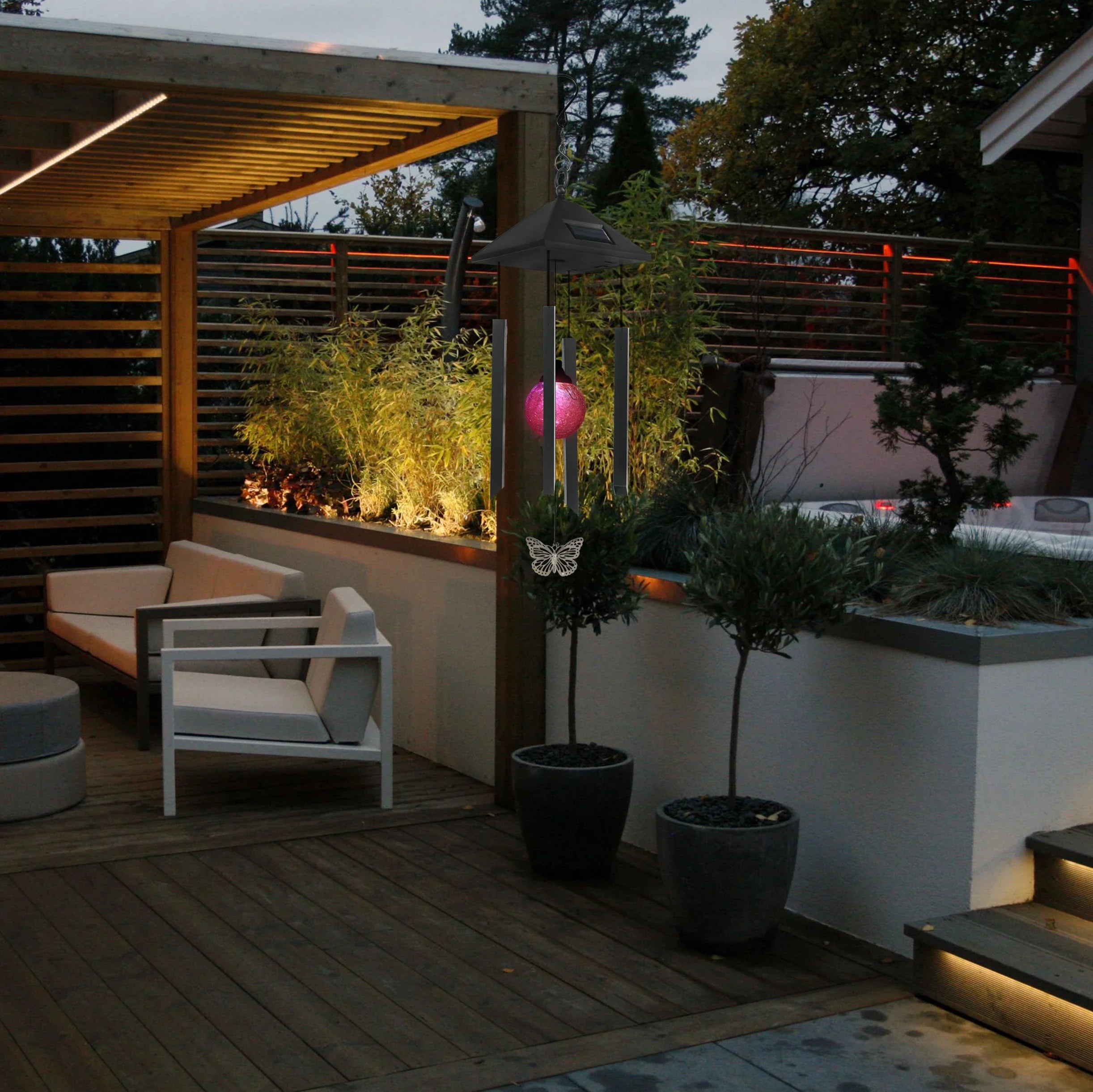 Modern outdoor patio pergola with wood slats and integrated lighting beside Solar LED Wind Chimes