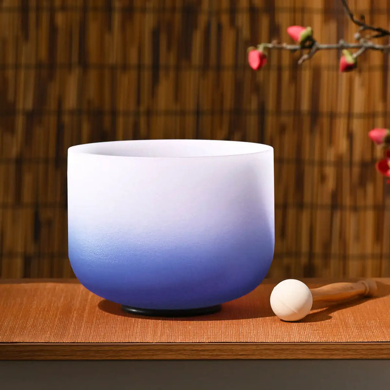 A gradient blue and white glass singing bowl with a smooth, rounded design.