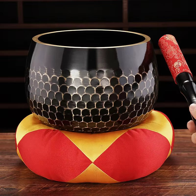 Black Tibetan Brass Singing Bowl with honeycomb pattern on red and yellow cushion