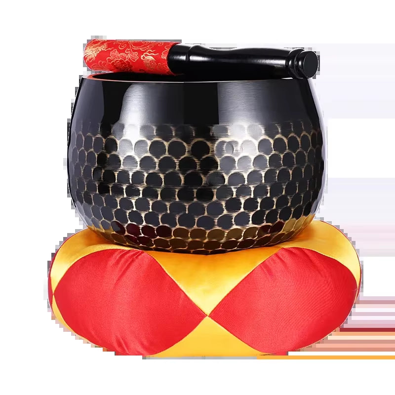 Black metallic Tibetan Brass Singing Bowl with honeycomb pattern on red and yellow cushion