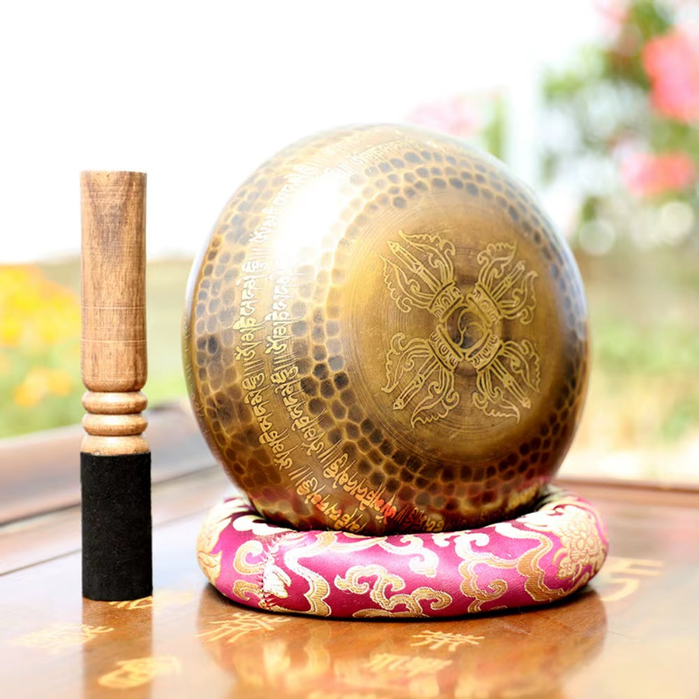 Tibetan Brass Singing Bowl on pink cushion with wooden striker for sound healing