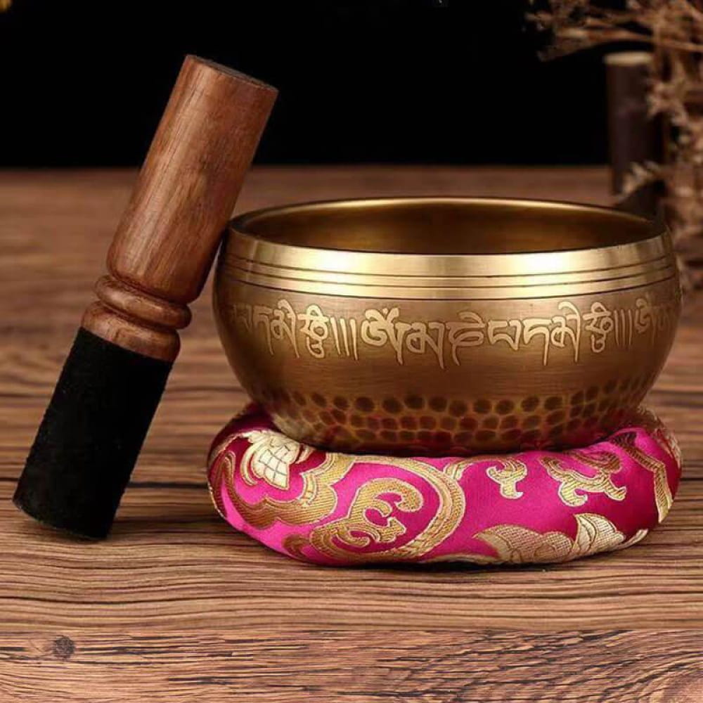 Tibetan Singing Bowl with striker on pink cushion for meditation and relaxation