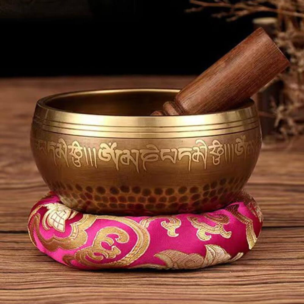 Tibetan Singing Bowl with striker on pink cushion for meditation and relaxation