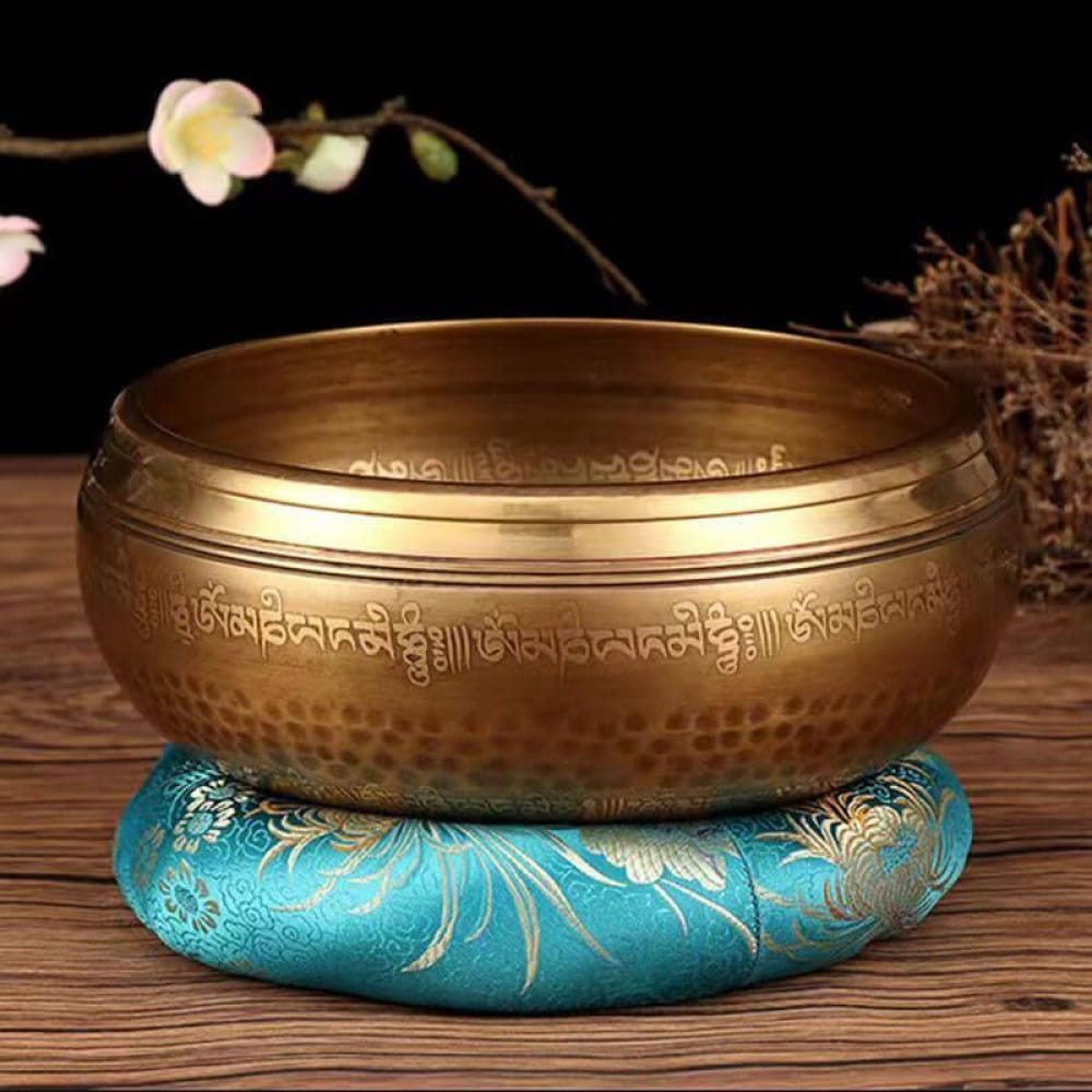 Brass Tibetan singing bowl on turquoise cushion with gold embroidery for meditation