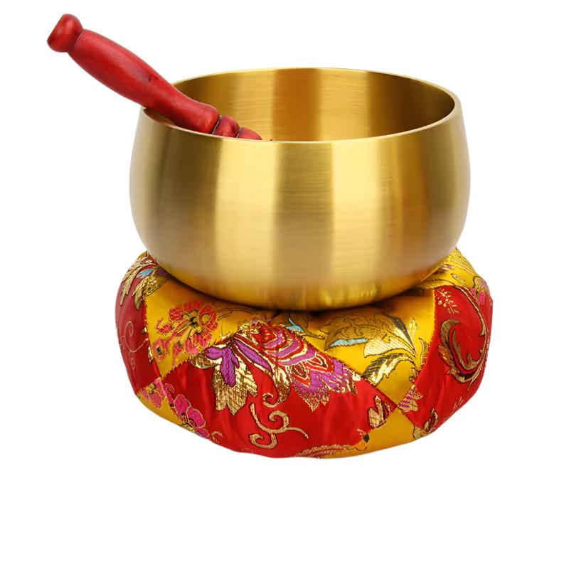 Golden Tibetan singing bowl with red striker on a floral cushion for meditation healing