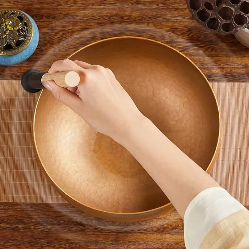 Golden Tibetan Singing Bowl played with a mallet for meditation and healing