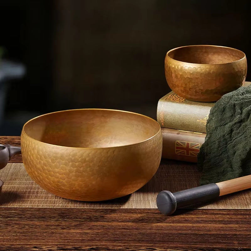 Hammered brass Tibetan singing bowls with a wooden striker for meditation and healing