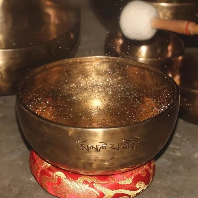 Tibetan Singing Bowl on red cushion with gold patterns for meditation and healing