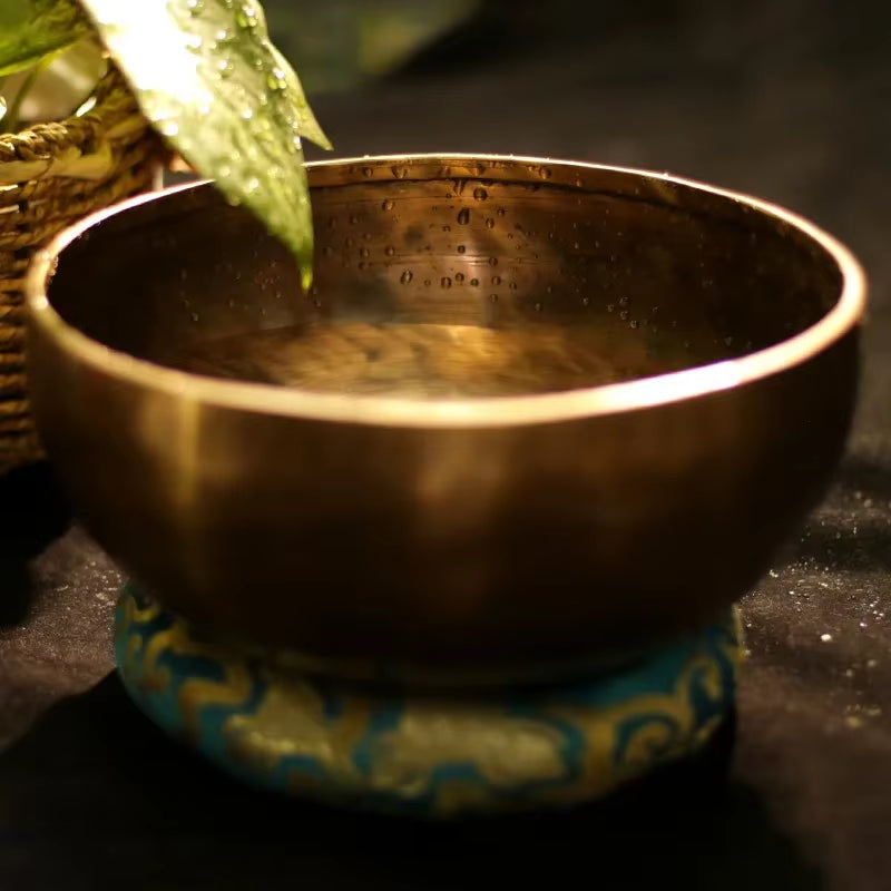 Tibetan Singing Bowl on a decorative turquoise cushion for meditation and sound healing