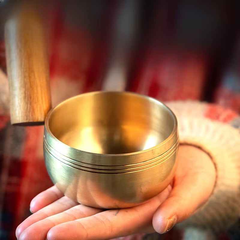 Golden Tibetan singing bowl in open palms for meditation and healing