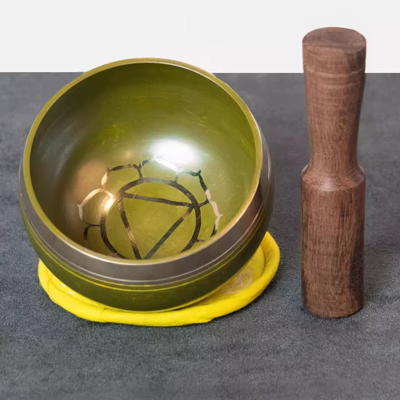 Brass Singing Bowl with geometric pattern on yellow cushion with wooden striker