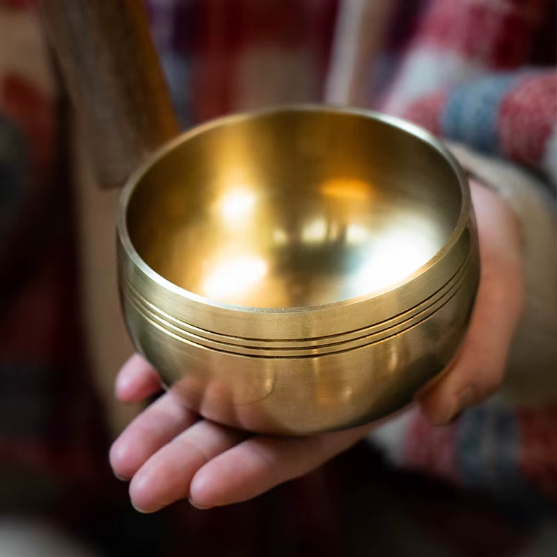 Golden Tibetan singing bowl in an open palm for meditation and healing