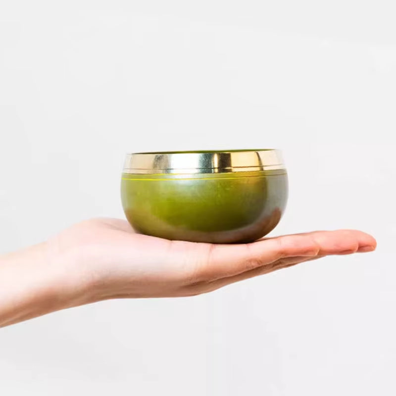 Green matcha tea in metallic bowl on palm for Tibetan Singing Bowl Set meditation