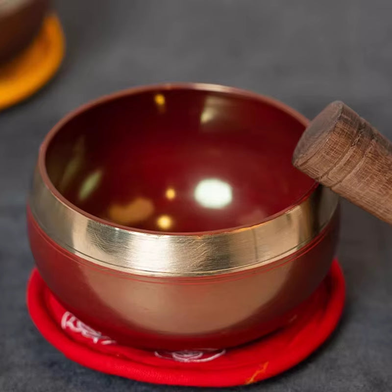 Tibetan Singing Bowl with wooden striker on red cushion for meditation and healing