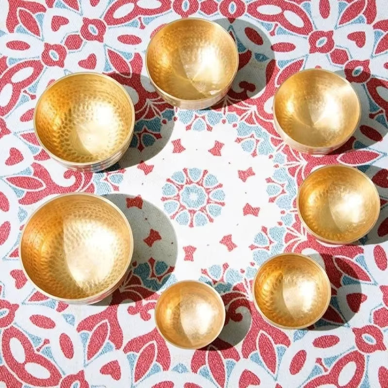 Seven hammered gold metallic bowls in a circular arrangement for sound healing