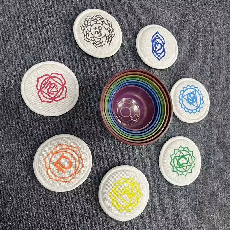 Circular chakra stones around a rainbow bowl with spiritual symbols for sound healing