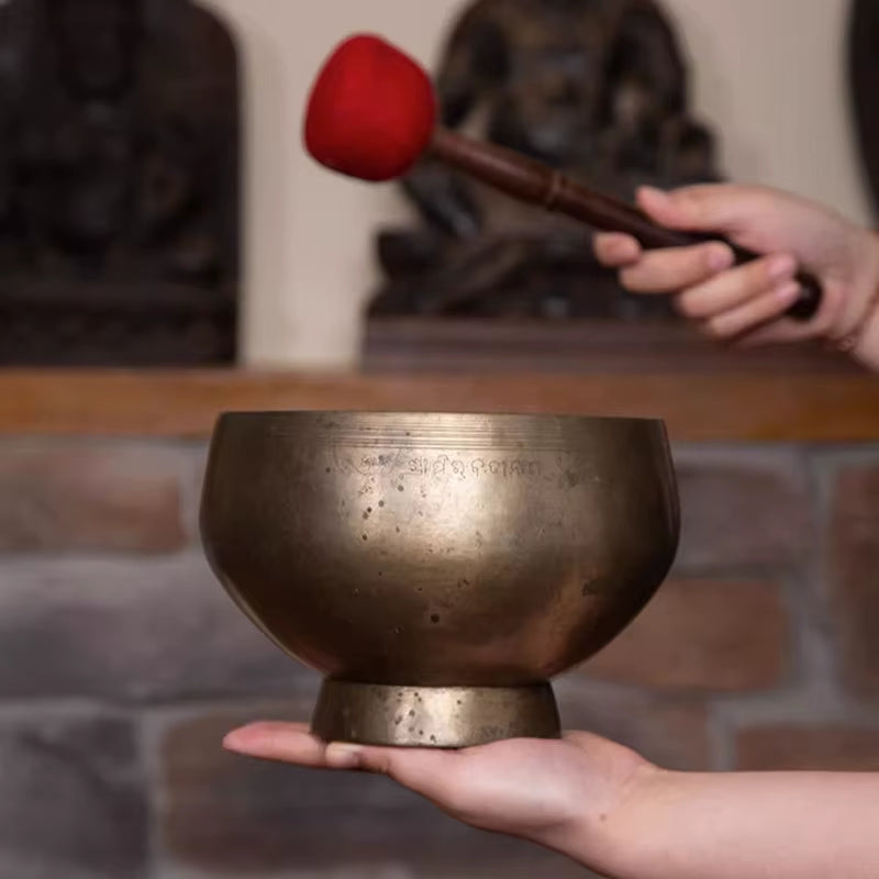 Metal Tibetan Singing Bowl being struck with a mallet for sound healing therapy