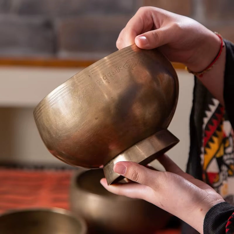 Bronze Tibetan singing bowl held by hands for sound healing therapy