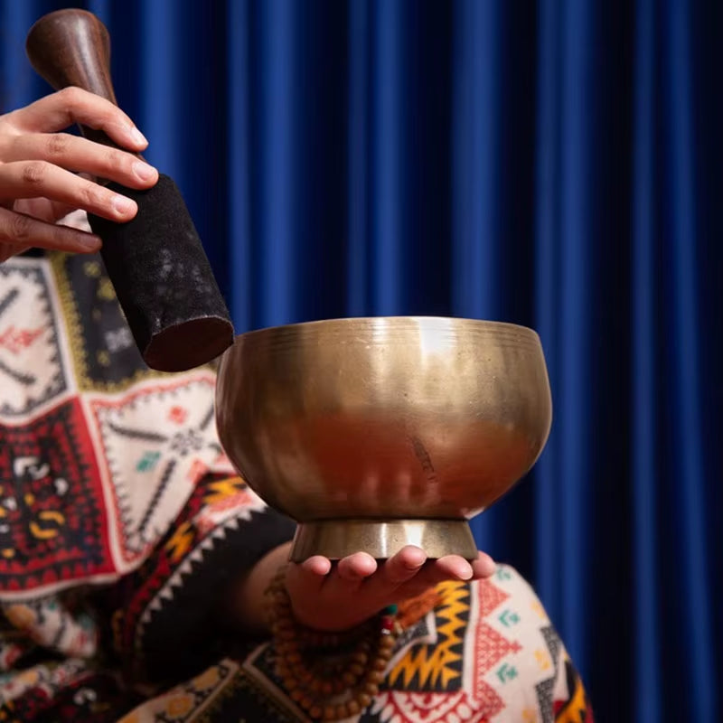 Tibetan singing bowl struck with wooden mallet for sound healing therapy