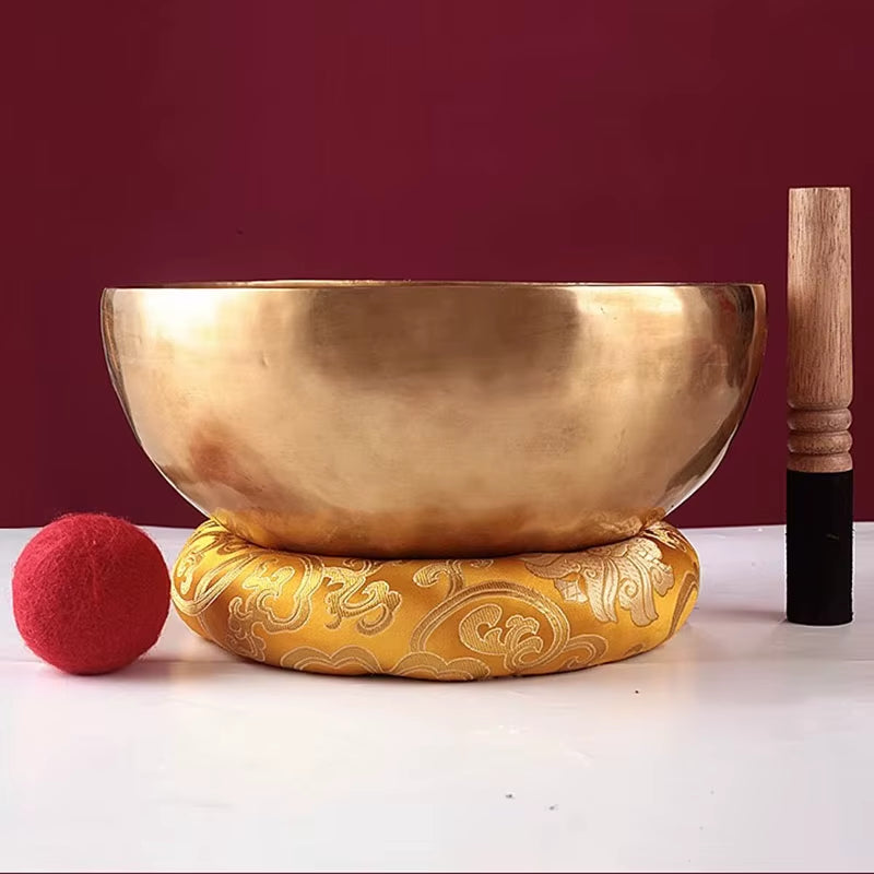 Golden Tibetan singing bowl on yellow cushion for meditation and healing