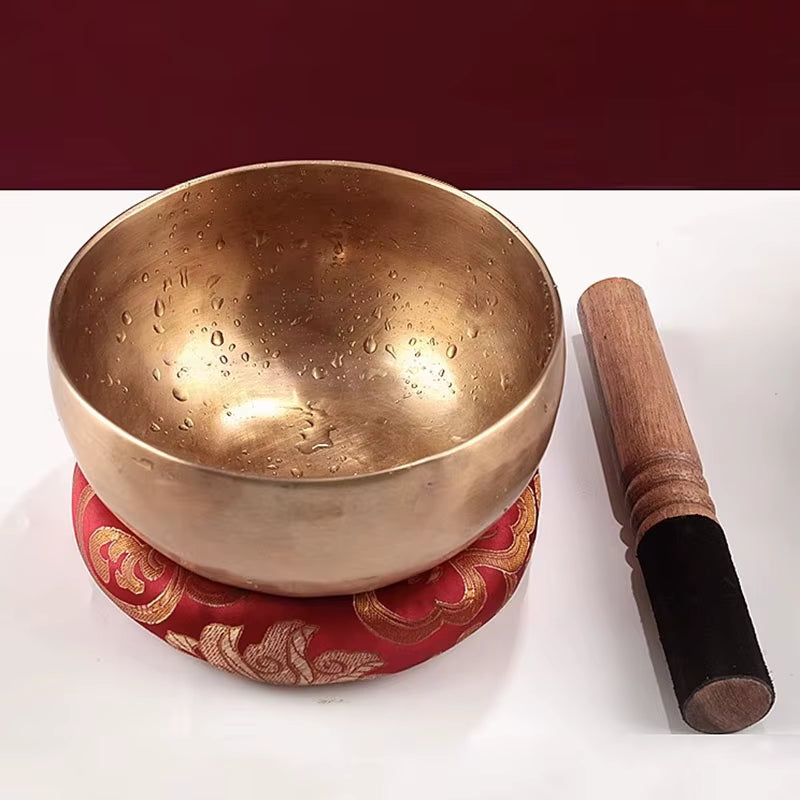 Tibetan Singing Bowl with Wooden Striker on Red Cushion for Meditation and Healing