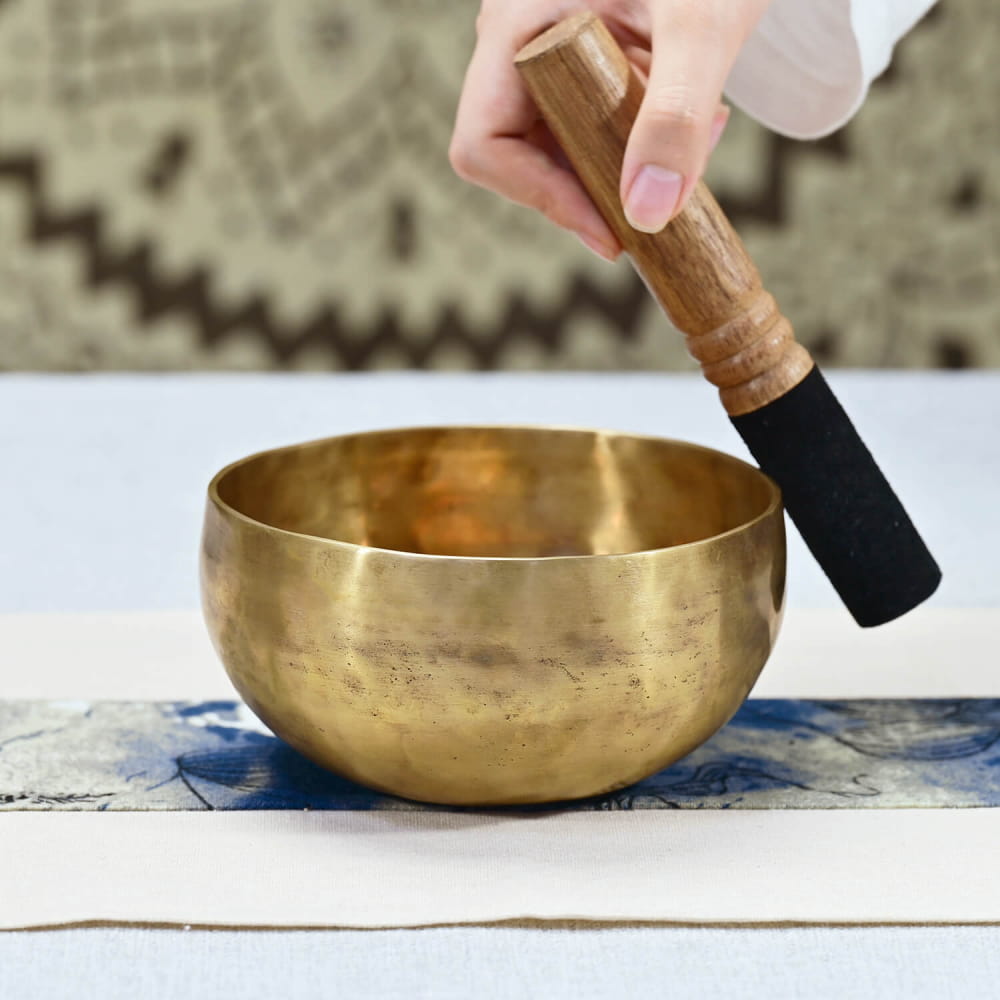 Golden Tibetan singing bowl with wooden striker for meditation and sound healing