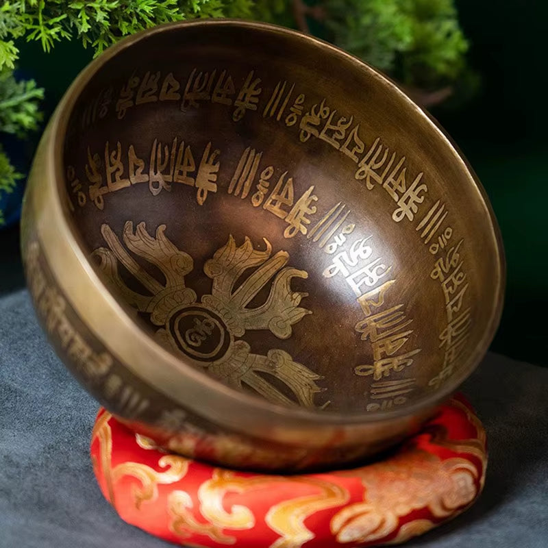 Tibetan singing bowl with etched designs on a red cushion for meditation from Nepal