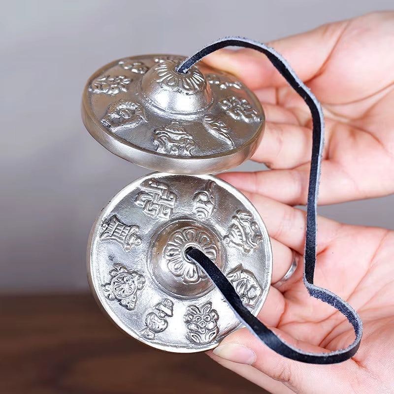 Tibetan Tingsha Hand Cymbals connected by a blue cord for meditation and yoga