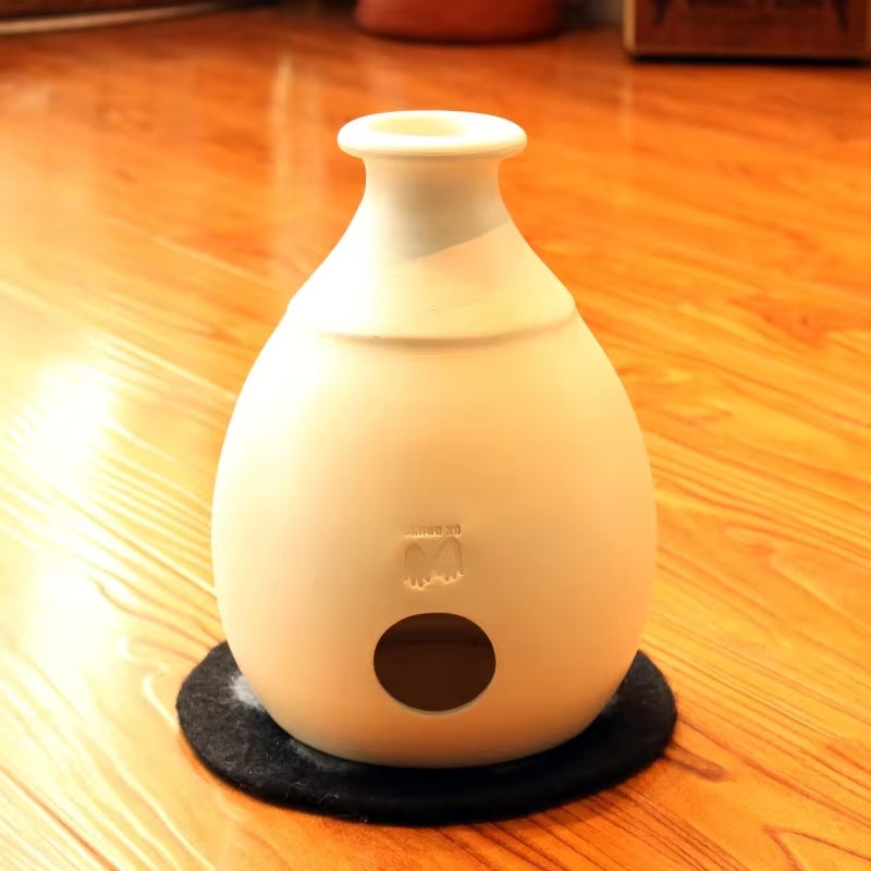 White ceramic vase diffuser with circular opening on Udu Drum African percussion drum