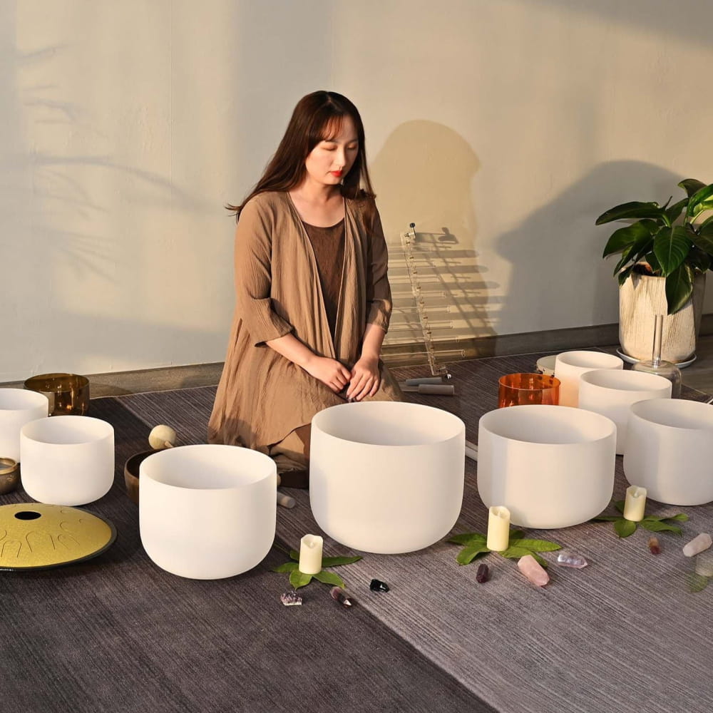 White crystal singing bowls arranged in a row on a gray surface for soothing sound therapy