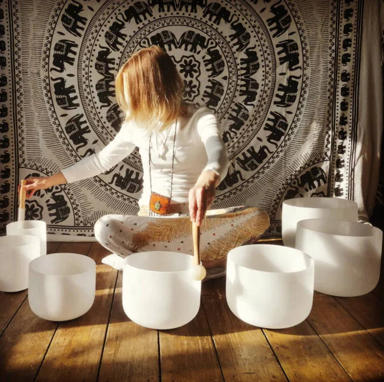 White Frosted Crystal Singing Bowl Set arranged in a semicircle on wooden flooring