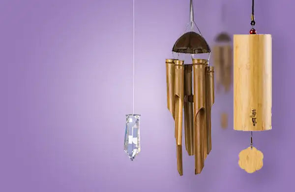 A sleek, transparent crystal chime hangs from a thin wire against a soft purple backdrop.
